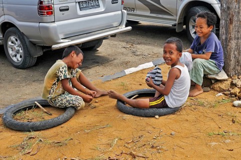 Children playing with old motorbike tyres, Labuan Bajo, Flores Island, Indonesia, Asia