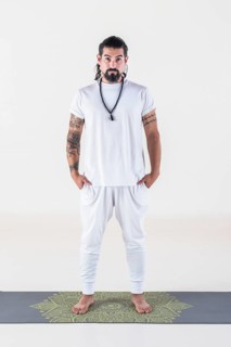 Portrait of a man dressed in white yoga clothes over white background while looking at camera.