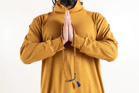 Close up of a man clasping hands while holding a japa mala over white background
