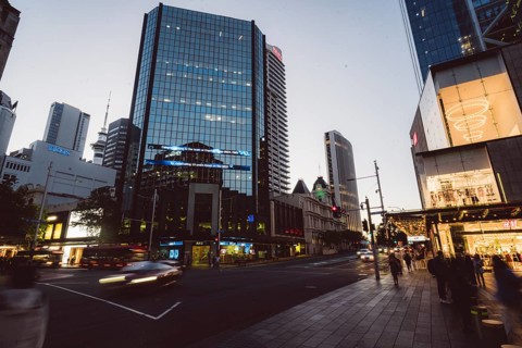 View of a busy street scene with modern skyscrapers and passers-by at dusk, new Zealand stock