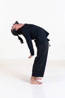 A man dressed in black doing yoga over white background. Suryanamaskar yoga pose. Studio shot