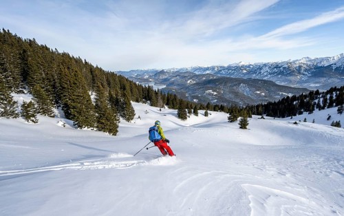 Skiers skiing down the Simetsberg, view of Walchensee and mountain panorama, Estergebirge, Bavarian