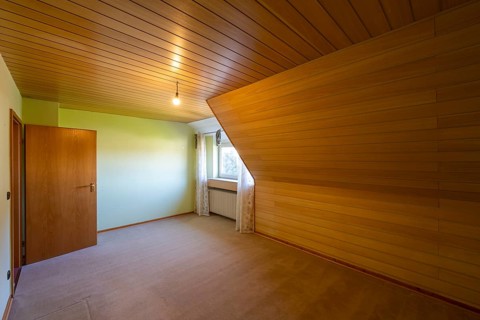 Renovated room in an old building without furniture, brown ceiling panels and wall panels, carpeted