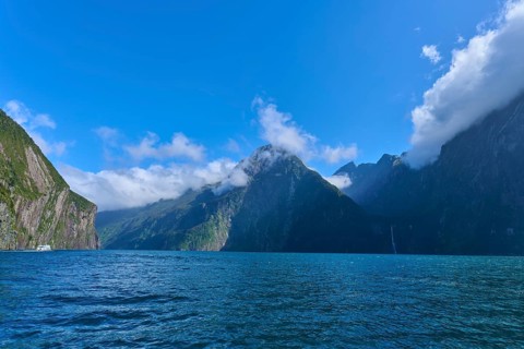 Clear blue waters surrounded by high mountains and clouds, summer, Milford Sound, Te Anau,