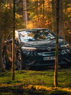 Car between trees in the forest with sunbeams on the bonnet, car sharing vehicle Deer Mobility,