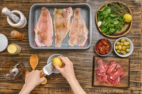 Hands rub the zest of lemon for sauce to cook juicy fish