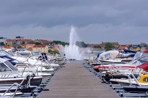 Boat mooring with boats in front of the island of Stakholmen with a view of the water fountain in