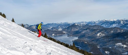 Skiers skiing down the Simetsberg, view of Walchensee and mountain panorama, Estergebirge, Bavarian