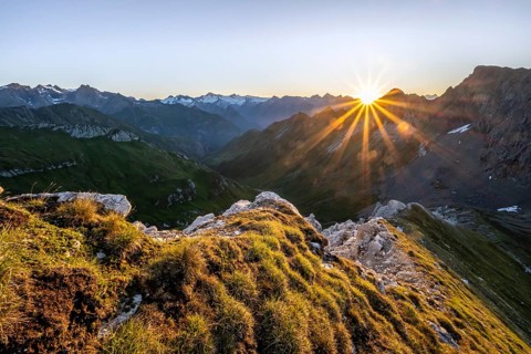 Mountain landscape at sunrise with sun star, view of mountain peaks of the Venediger group and into