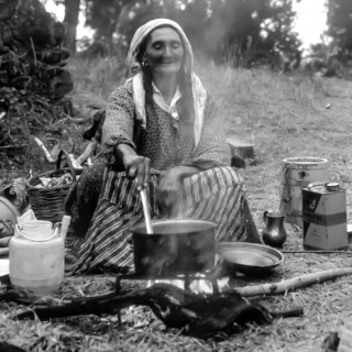 Woman cooking outside with firewood in the Peloponnese, Greece, Europe