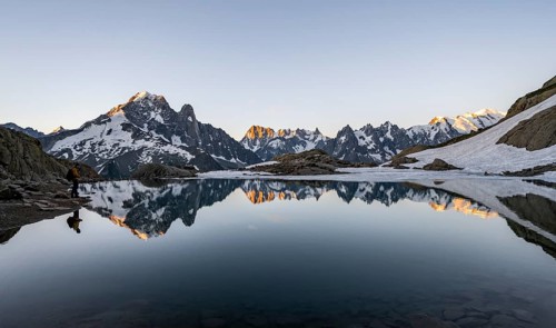 Tourist at a mountain lake in the morning, mountain landscape at sunrise, water reflection in Lac