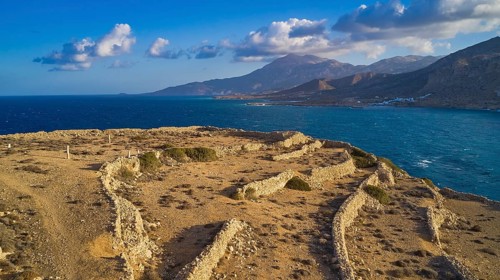 Drone shot, Archaeological excavation site, landscape of ruins by the sea with distant view of
