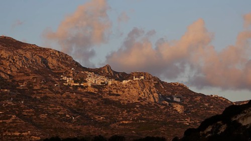 A village on a rocky plateau in a mountain range at sunrise under a cloudy sky, mountain village