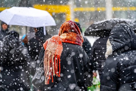 Winter weather, heavy snowfall, city centre traffic, passers-by in the snow, person with thick