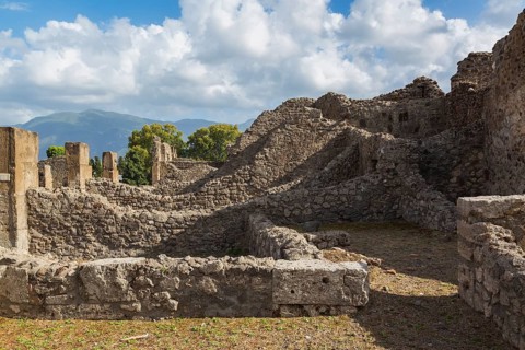 Old stone wall structures of varying heights and remnants of residential buildings at the ancient
