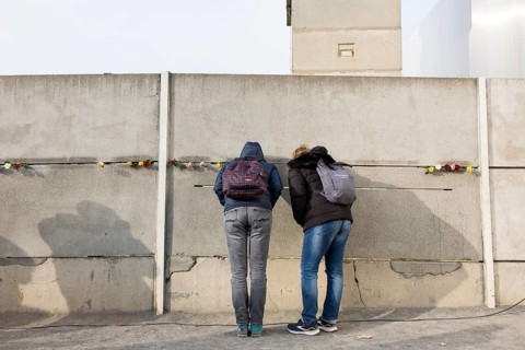 Two visitors look through a gap in the Wall at the central commemorative event at the Berlin Wall