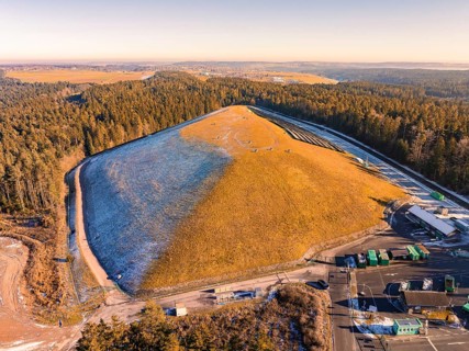 Panoramic view of a grassy hill and neighbouring forests, partly snow-covered, landfill, Neubulach,