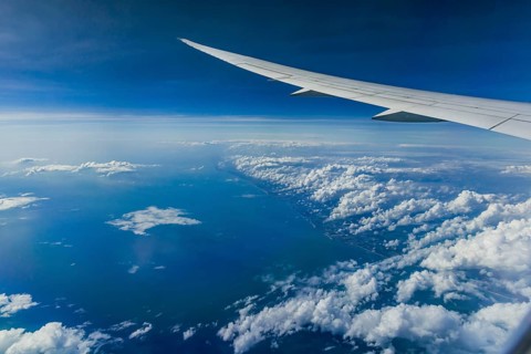 Above the clouds over the Indian Ocean. On the left, the coast of India. View from the aircraft