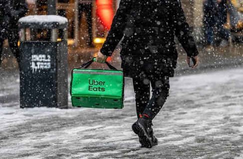 Winter weather, heavy snowfall, city centre traffic, courier of the delivery service Uber East, on