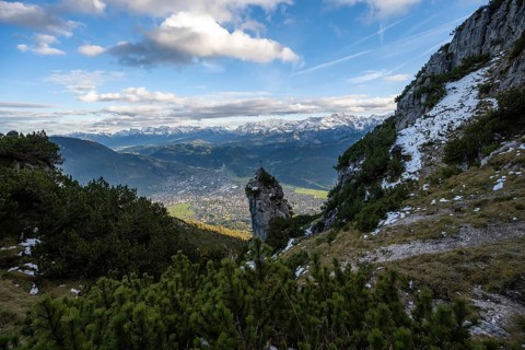 Rocky peak with summit cross, view of Garmisch-Partenkirchen and mountain panorama, hike to