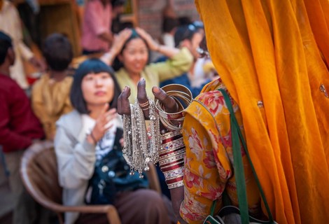 Woman in traditional Rajasthani dress selling jewellery to Japanese tourists, old town of Pushkar