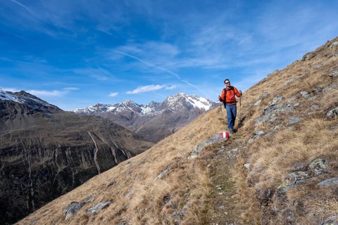 Mountaineers on a hiking trail in Niedertal, snow-covered mountain peaks of the Ötztal Alps with