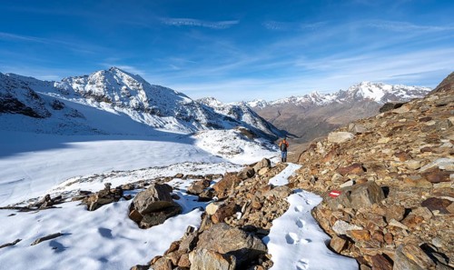 Mountaineer on a hiking trail with snow, descent from Ramoljoch at Spiegelferner, autumnal mountain