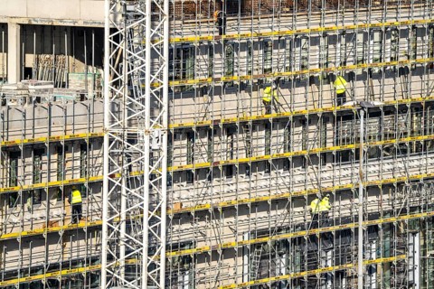 Large construction site, scaffolded new building, factory and office building, workers on the