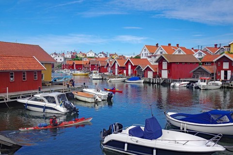 Harbour with many boats and traditional red houses under a blue sky, Coast, Gullholmen, Västra