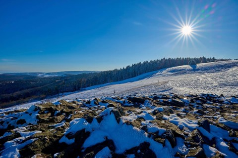 Snow-covered landscape under the bright sun, surrounded by rocks and forests, Abtsroderkuppe,