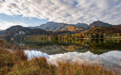 On the shore of Lake Lake Kochel with reflection, autumn landscape with mountain peaks Herzogstand