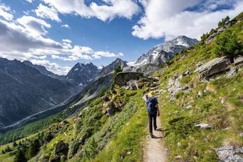 Mountaineer on a hiking trail, mountain landscape near Arolla, behind mountain peak Mont Collon and