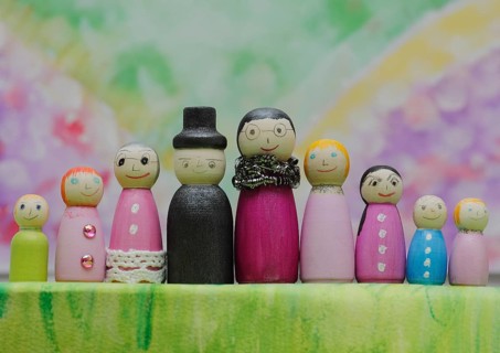 Nine funny painted wooden cones man and woman large and small in front of a colourful painted
