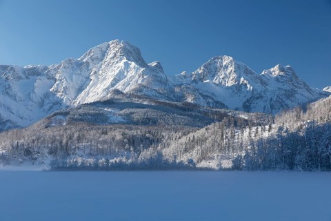 Lake Almsee frozen and snowcovered with the Totes Gebirge mountains in the background