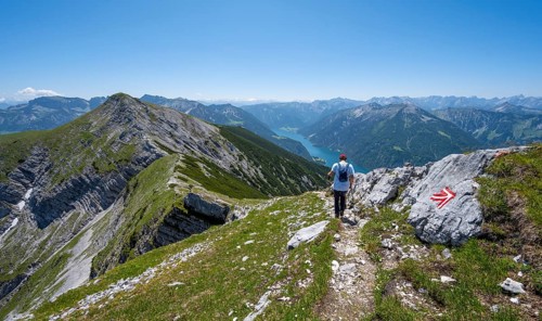 Mountaineer on the hiking trail on the summit ridge of the Unnütz, behind Achensee and summit of