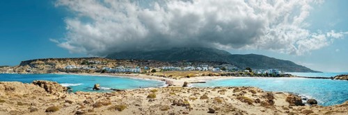 A wide panorama at Frangolimiona sandy beach with mountains and clouds under a blue sky, Arkasa,