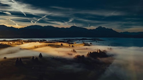 Autumn sunrise in the foothills of the Alps with fog at Illasbergsee and Forggensee near Halblech