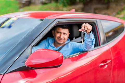 Smiling driver showing car key. Young male driver showing the keys to his car