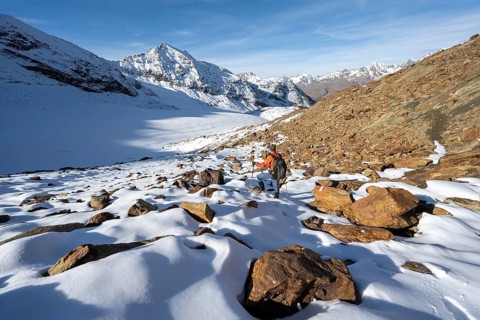 Mountaineer on a hiking trail with snow, descent from Ramoljoch at Spiegelferner, autumnal mountain