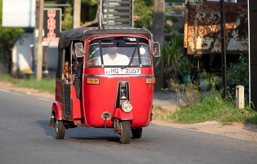 Red tuk tuk or autorickshaw with Sri Lankan passenger, Veyangoda, Western Province, Sri Lanka, Asia