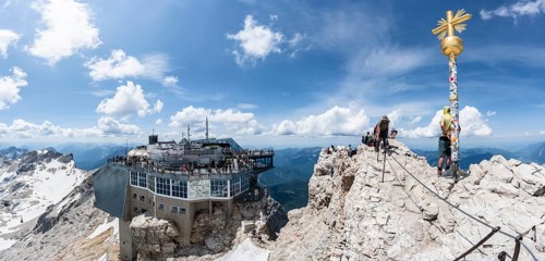 Summit of the Zugspitze with golden summit cross and modern mountain station of the Bavarian