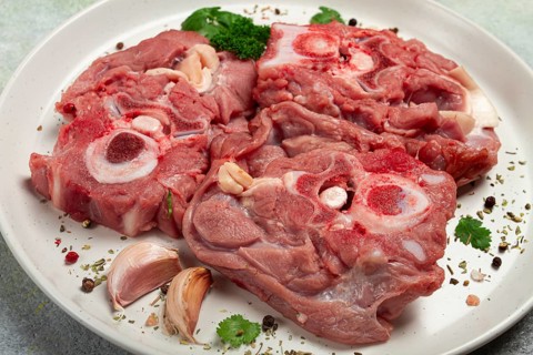 Raw steak, calf's neck on the bone, fresh meat, on a white plate, top view, no people