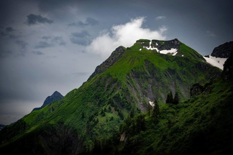 Grassy summit with remnants of snow and dramatic clouds, Lech, Lechquellengebirge, Vorarlberg,
