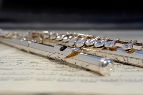 Transverse flute lying on a sheet of music, musical instrument in silver