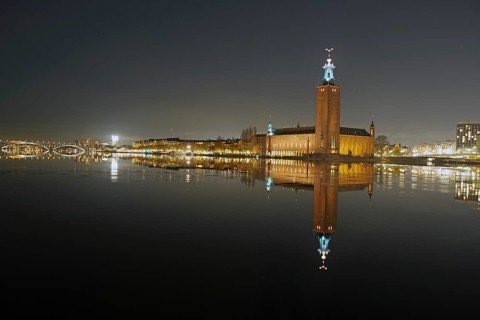 Illuminated building reflected in calm water at night, with a clear dark sky, capital city, city