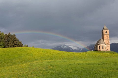 Church St. Kathrein, 39010 Hafling, Italy with a rainbow in the background. The church is from the