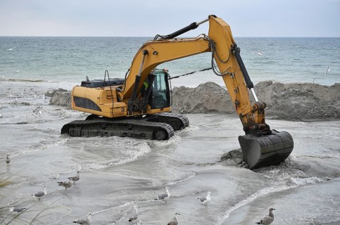Excavators working to reclaim land on the beach of the Darß peninsula, Mecklenburg-Western