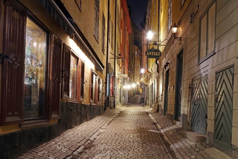 Narrow, illuminated cobblestone alley at night with old charming buildings, winter, Gamla Stan, Old