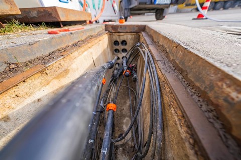 Open manhole with numerous cables and pipes at a construction site, Wend Glasfasermontage