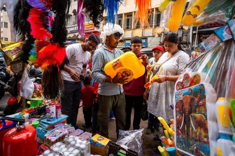 People buy Holi celebration items in a market on the eve of Holi Festival, on March 13, 2025 in